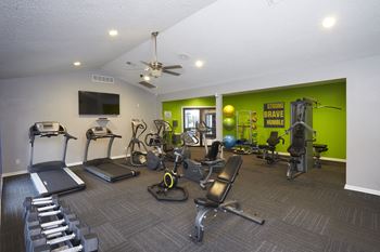 A gym with a variety of equipment including treadmills, weights, and exercise machines.